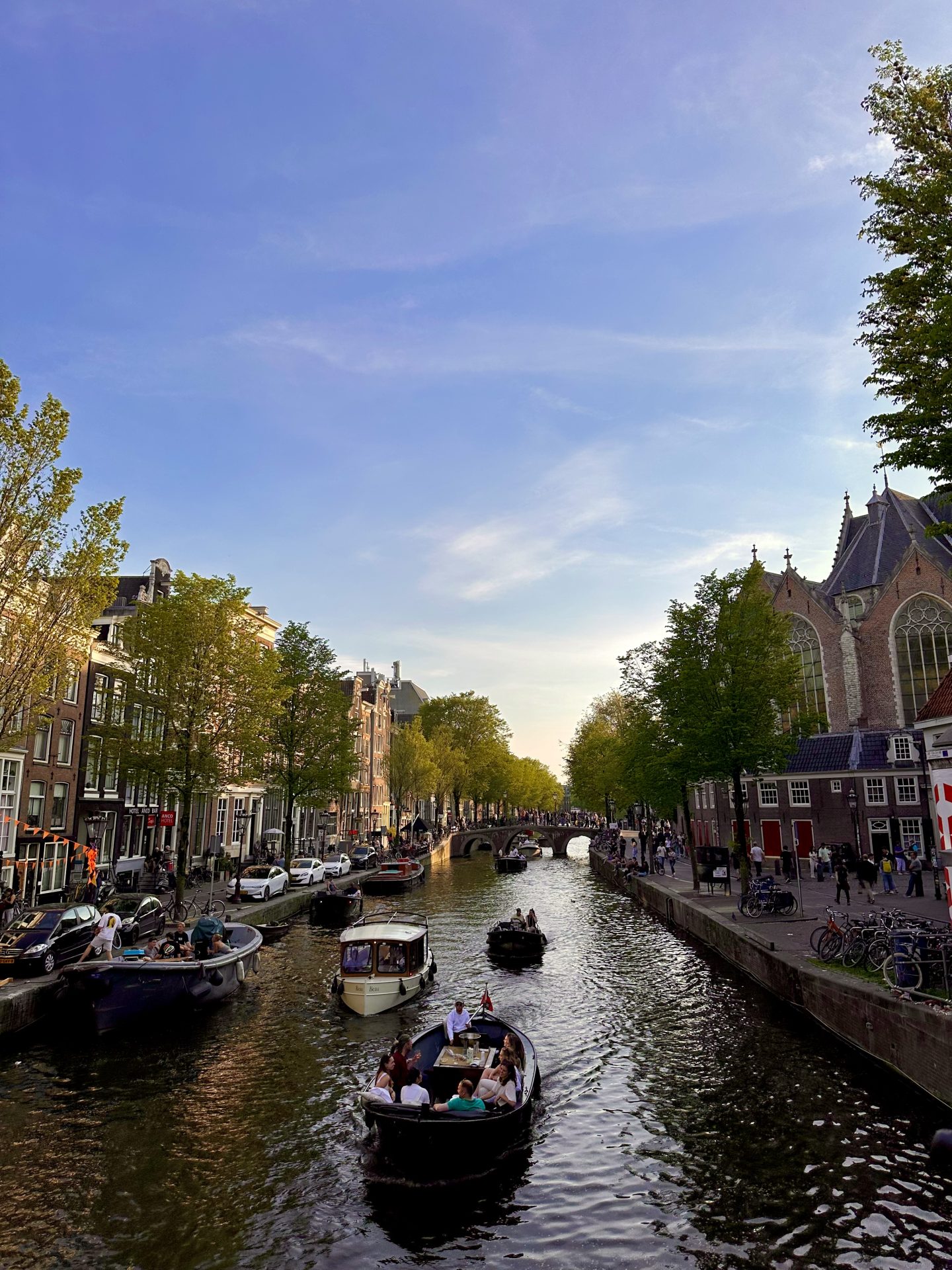 Vista de un canal de Ámsterdam con puente, barcos y casas históricas en el centro